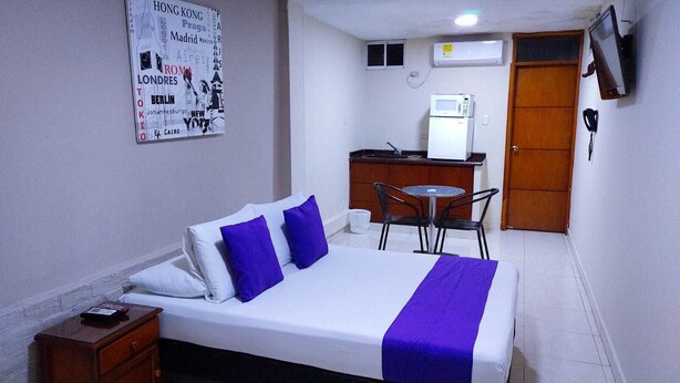 A hotel room with a bed, a desk, a chair, and a microwave.
