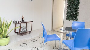 A room with a round table and blue chairs, a potted plant, and a wall-mounted green plant.