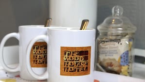 Two white mugs with "The Woodhouse Hotel" logo, a clear glass jar with biscuits, and a white tray with a polka dot pattern. - The Woodhouse Hotel (Largs)