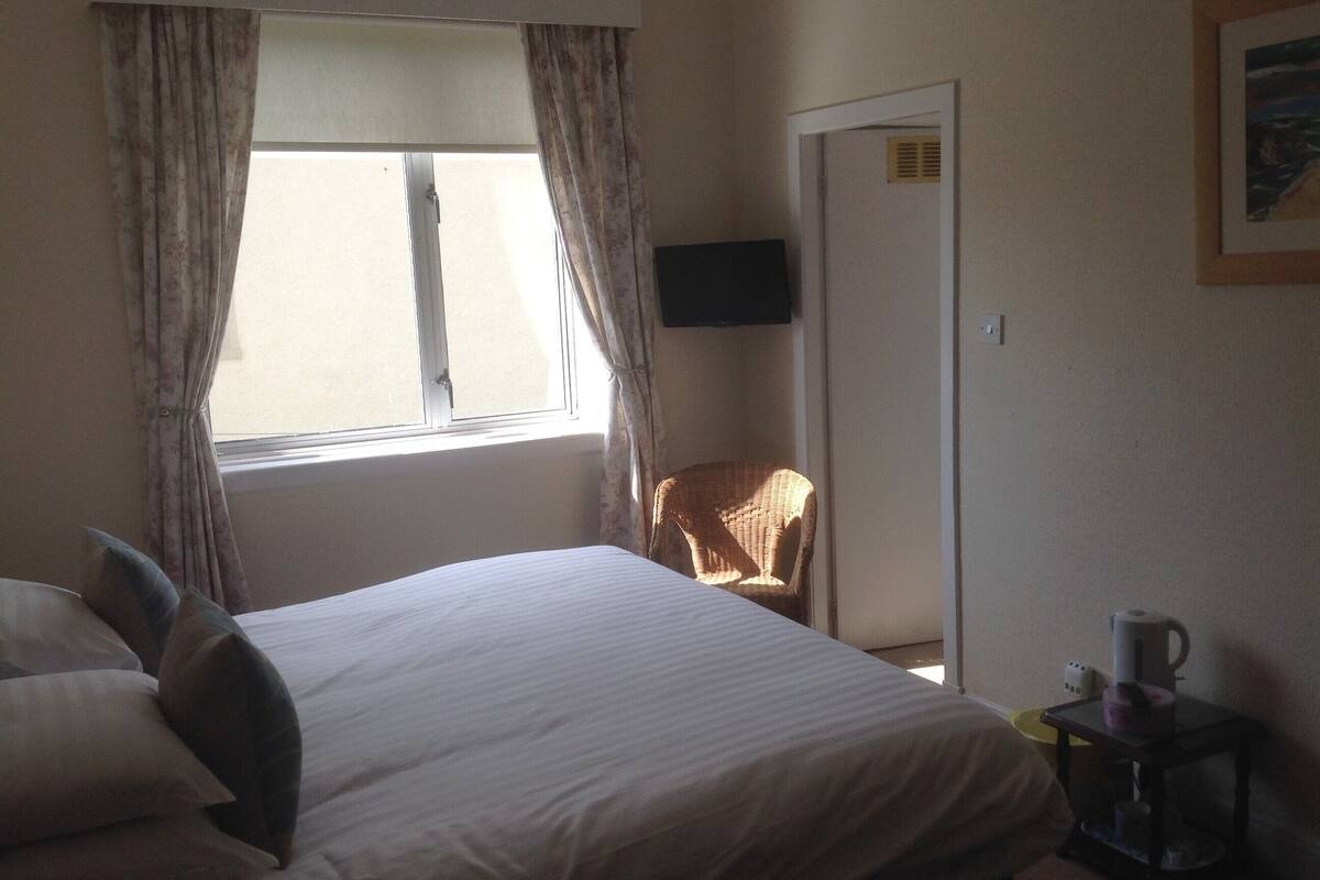A hotel room with a bed, a chair, a coffee table, and a painting on the wall.