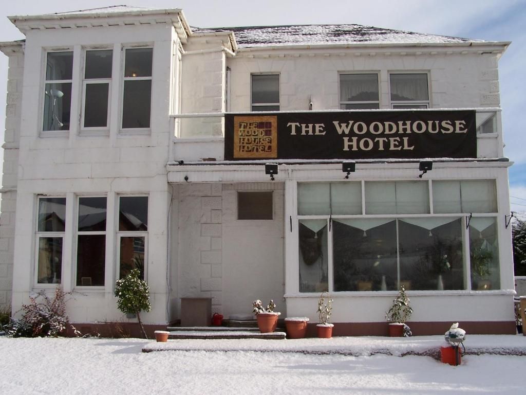 A two-story hotel with a prominent sign reading 'The Woodhouse Hotel.'