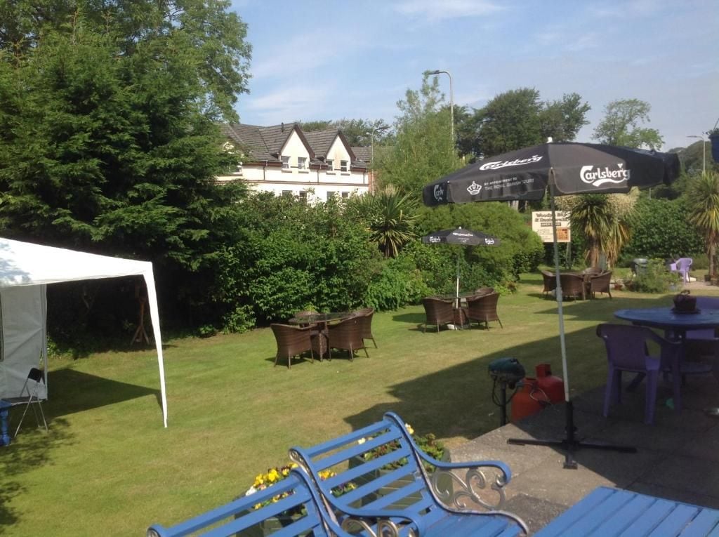 An outdoor seating area with tables and chairs, a tent, and a large umbrella.