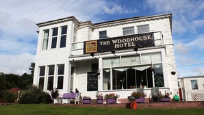 The Woodhouse Hotel with a prominent sign, large windows, and outdoor seating area. - The Woodhouse Hotel (Largs)