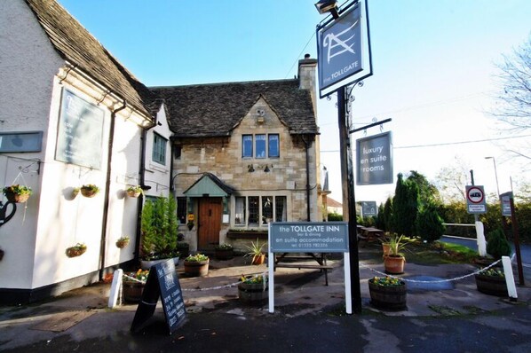 A traditional stone building with a sign for 'The Tollgate Inn' offering bar and dining.