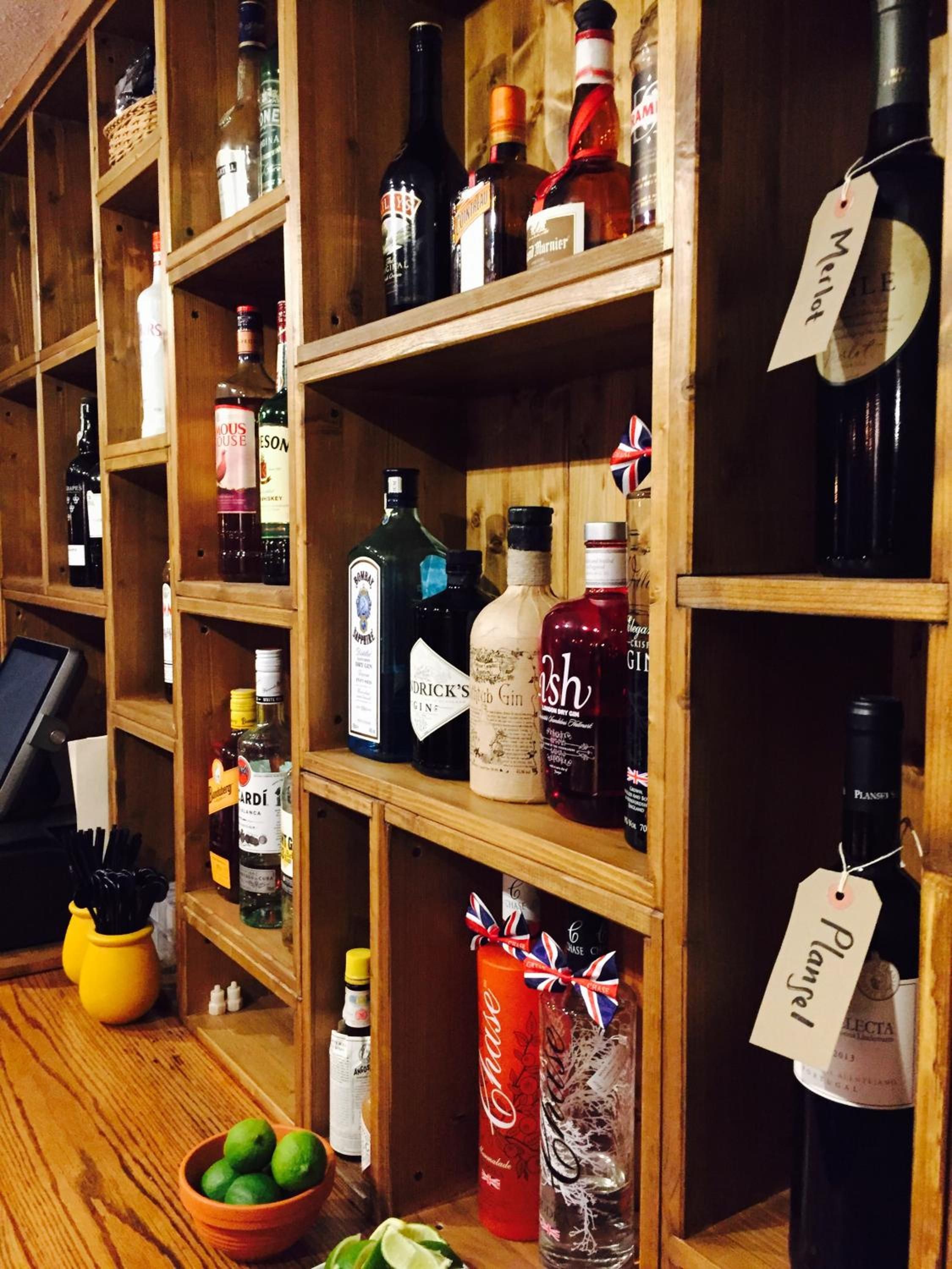 A liquor store with shelves stocked with various bottles of alcohol, a cash register, and a bowl of limes.