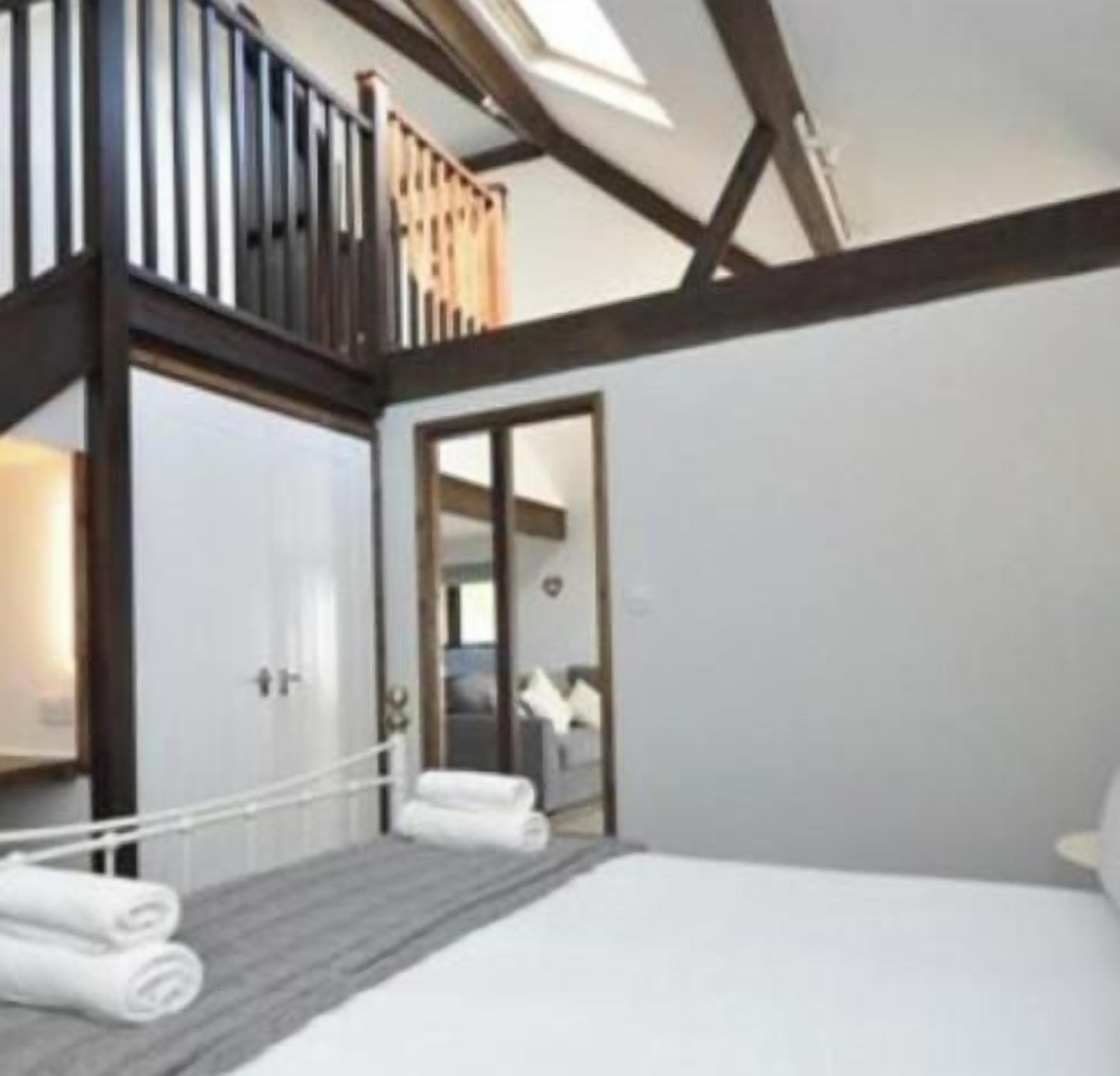 Un dormitorio con cama, techo de madera y vistas a un balcón.