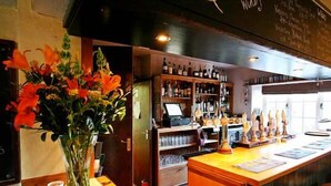 A bar area with a wooden counter, a selection of bottled beverages, and a chalkboard menu. - The Tollgate Inn (Trowbridge)