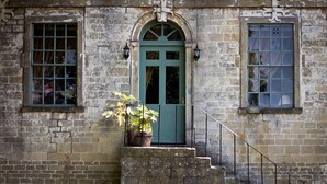 A stone building with a green door, a sign reading "HAM GREEN," and a potted plant on the steps. - The Tollgate Inn (Trowbridge)