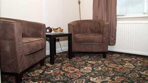 A room with two armchairs, a small table, and a patterned carpet. - The Grainary Farm Stay (Scarborough)