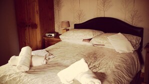 A neatly made bed with rolled towels, a bedside lamp, and a wardrobe in a hotel room. - The Grainary Farm Stay (Scarborough)