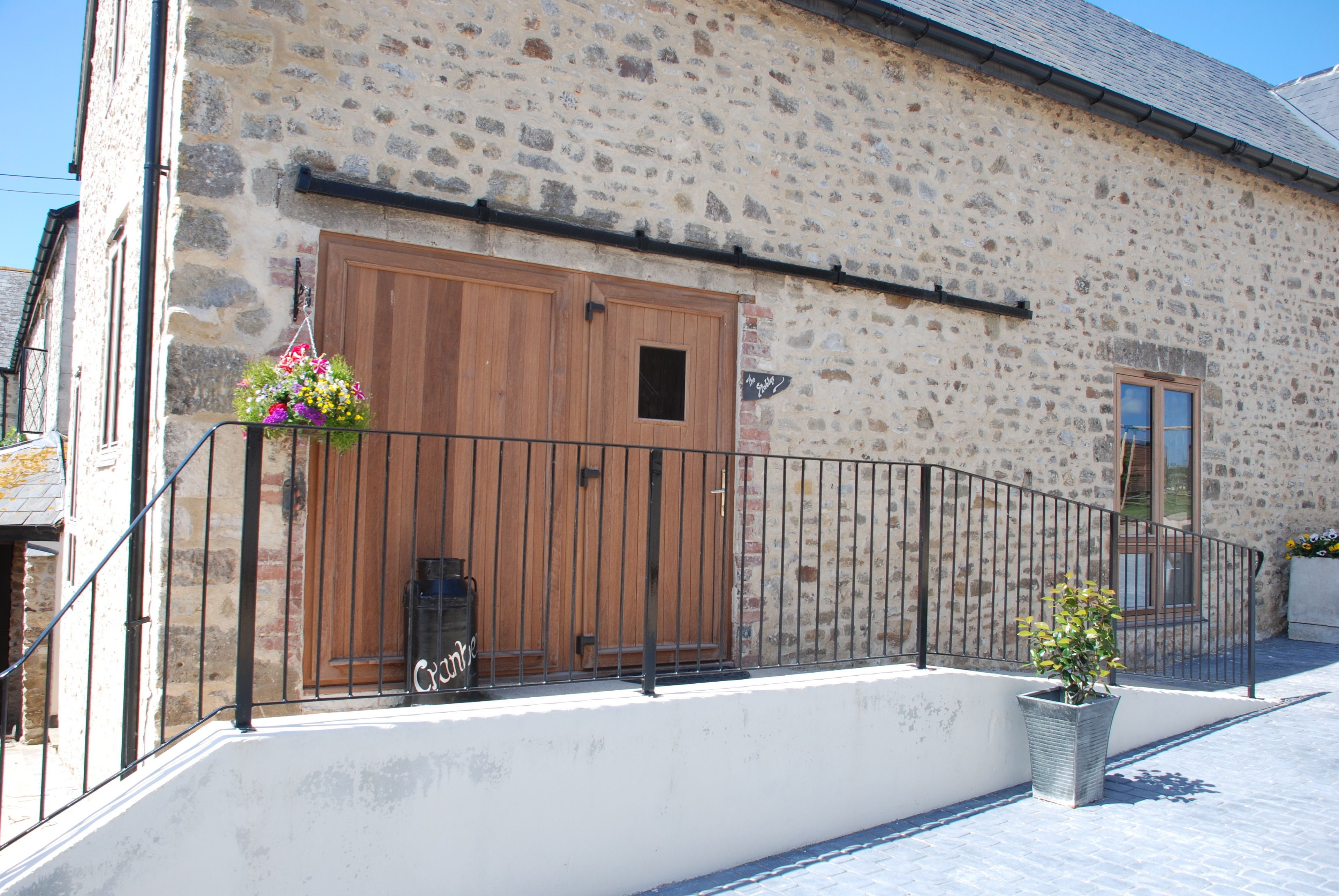 A stone building with a wooden door and a metal railing.