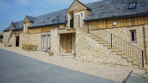 A stone building with wooden exterior, a staircase, and a bench. - HILLS FARM STAYS (Axminster)