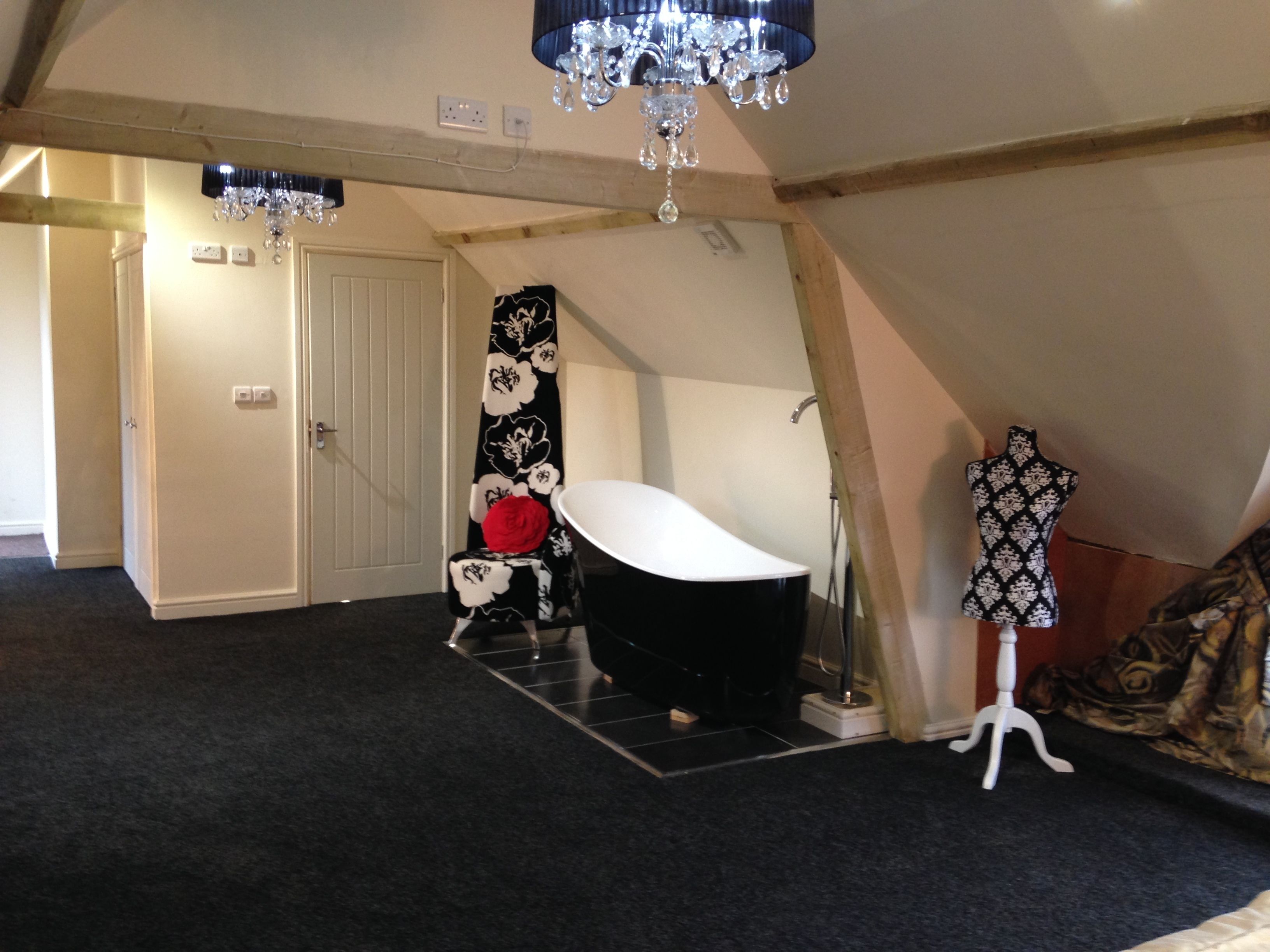 A room with a black bathtub, a white door, and a chandelier.