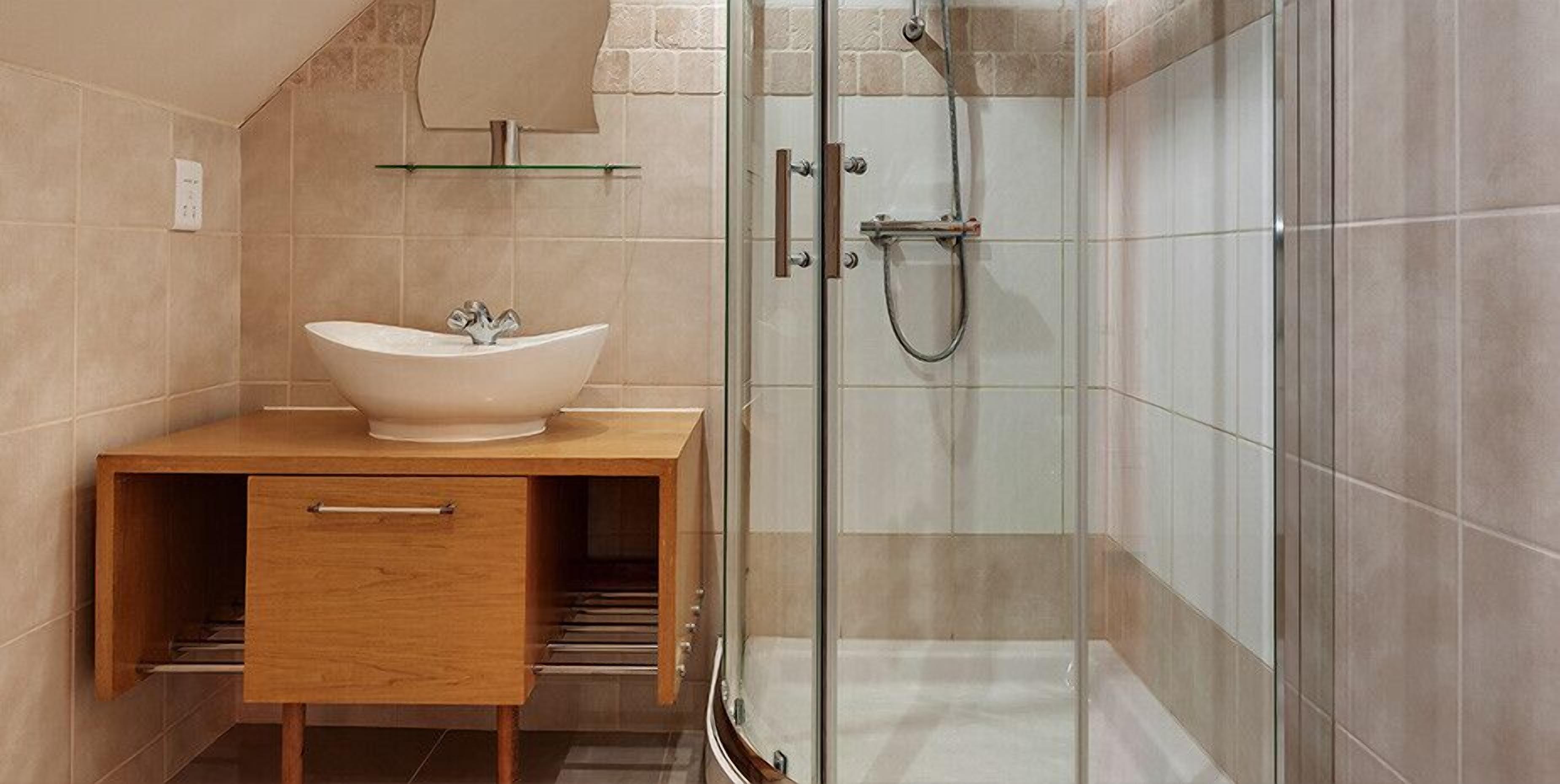A modern bathroom with a freestanding sink, a glass shower enclosure, and a wooden vanity.