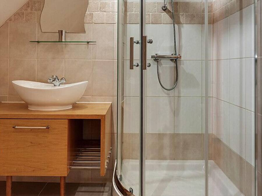 A modern bathroom with a freestanding sink, a glass shower enclosure, and a wooden vanity.