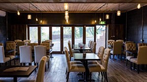 A restaurant with wooden ceiling and walls, large windows, and multiple dining tables and chairs. - HILLS FARM STAYS (Axminster)