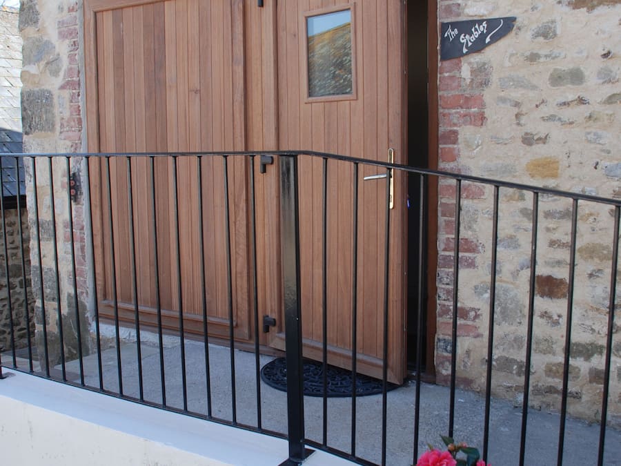 A stone building with a wooden door and a metal gate.