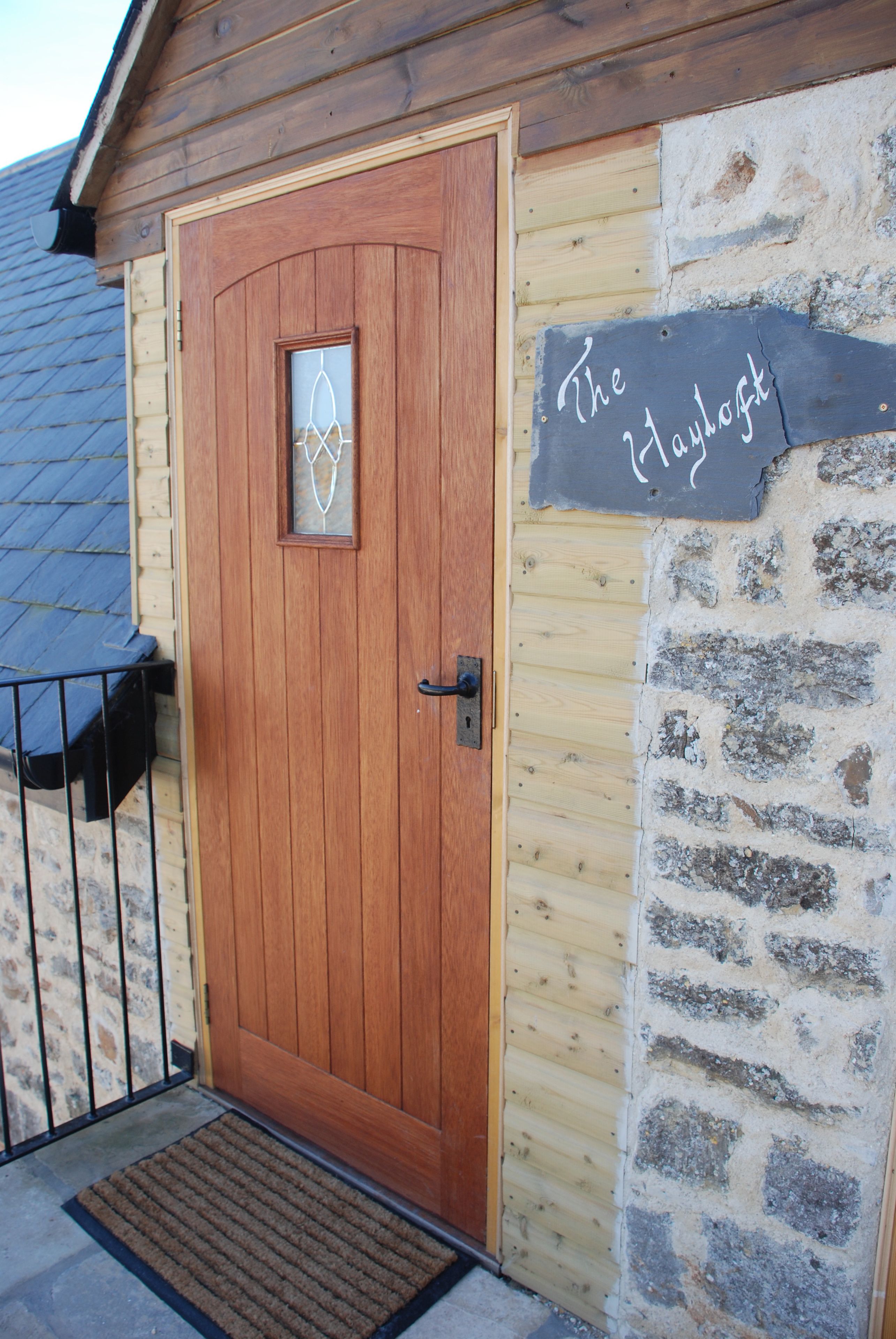 A wooden door with a glass panel and a sign reading "The Hayloft".