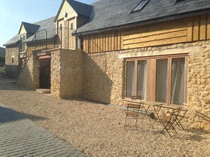 A stone building with a wooden balcony and a gravel driveway.