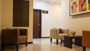 Un vestíbulo con una puerta marrón, un sofá color beige y un sillón marrón.