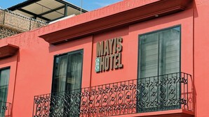 Un edificio con fachada roja y un letrero que dice "MAYIS HOTEL".