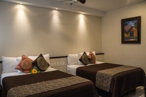A hotel room with two beds, each with patterned bedspreads and decorative pillows. - Hotel Mayis (Oaxaca)