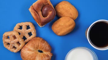 Diversos doces e uma chávena de café sobre um fundo azul.
