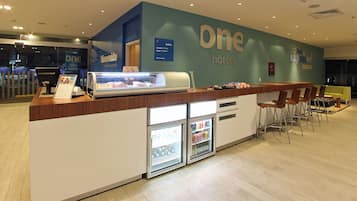 A reception area with a counter, a refrigerator, and a seating area with chairs.