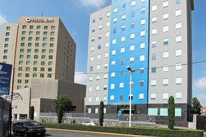Ein mehrstöckiges Hotel mit einem Fiesta Inn Schild, einer blau-beigen Fassade und einem verschlossenen Eingang.