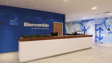 Un comptoir d’accueil avec un mur bleu et une pancarte sur laquelle on peut lire : « Bienvenido, nous vous attendons ».