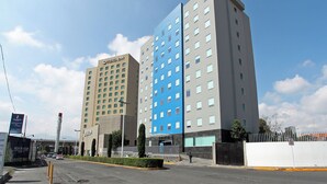 Een modern hotel met een opvallende blauwe gevel en een beige gebouw ernaast.