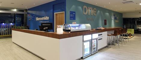A reception area with a blue wall, a wooden counter, and a refrigerator.