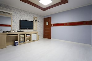 Une pièce avec un meuble en bois, une télévision, une porte et un interrupteur sur le mur.