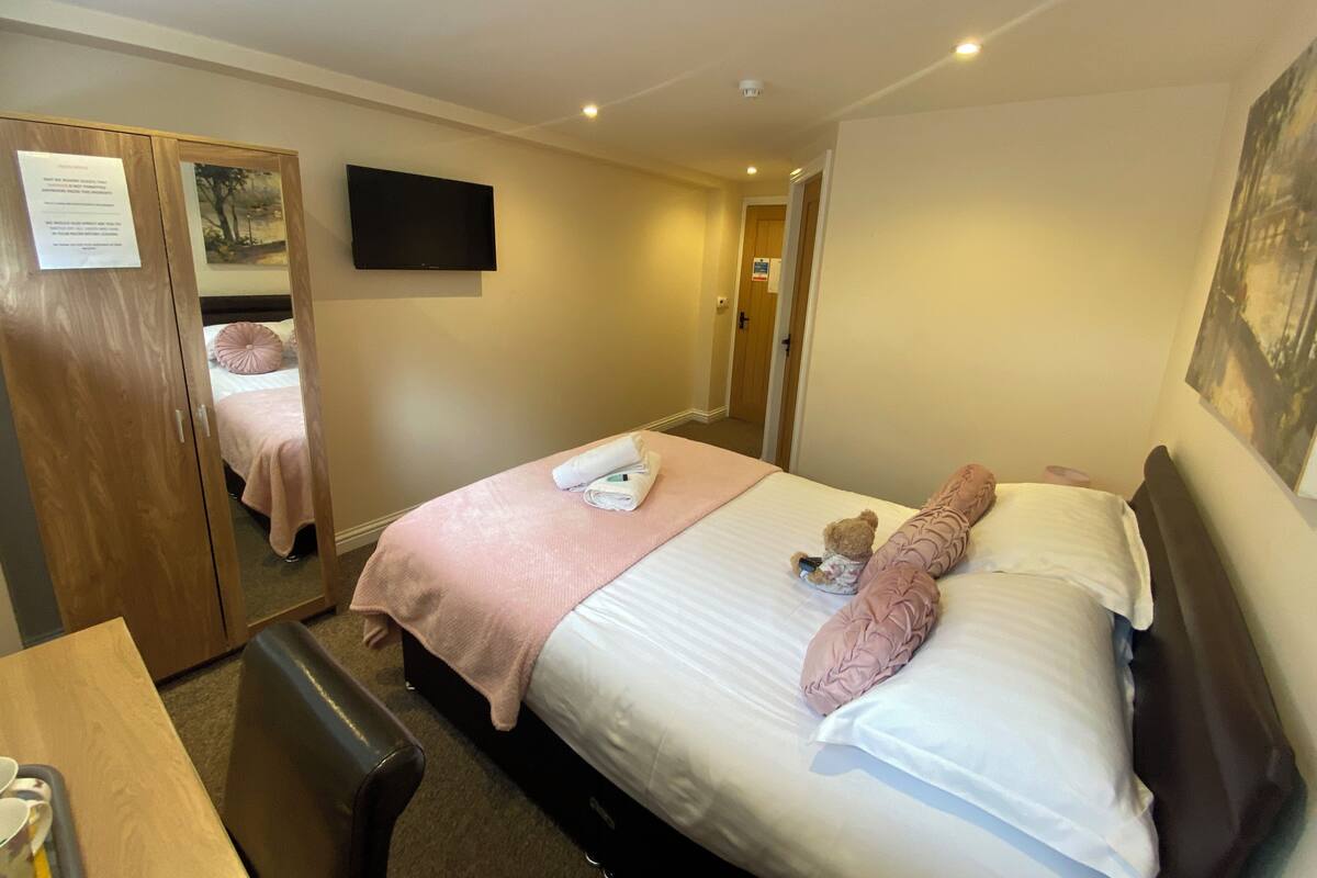 Une chambre d’hôtel avec un lit, un bureau, une chaise, une télévision et une porte.