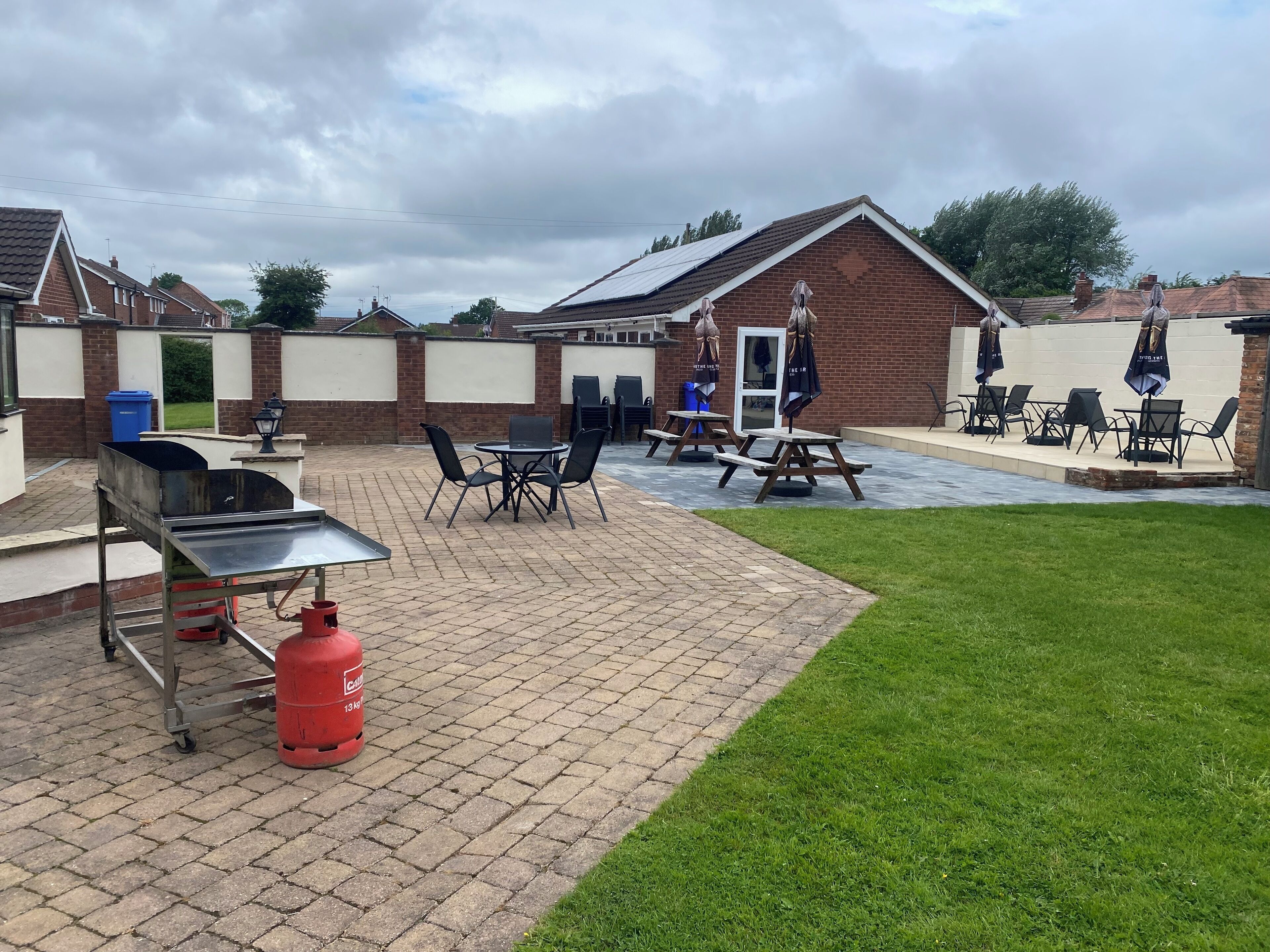 Een terras met tegels, zitplaatsen en een barbecue.