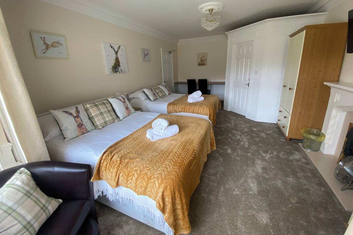 Une chambre d’hôtel avec deux lits, une armoire et un petit coin salon.