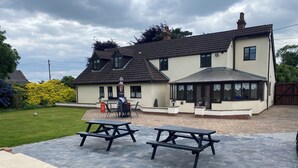 A two-story house with a patio area featuring picnic tables and a barbecue setup. - Parkside Guest House (Goole)