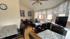 A dining area with tables and chairs, a ceiling fan, and a TV on a window sill. - Parkside Guest House (Goole)
