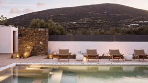 Un área de piscina con sillas de descanso y un muro de piedra.