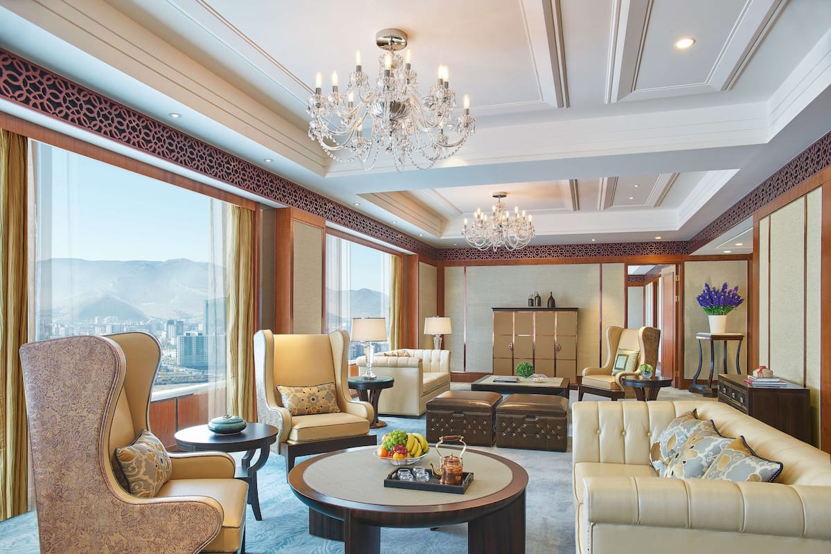 Een ruime hotel lobby met een grote kroonluchter, comfortabele zitplaatsen, uitzicht op de stad en een traditionele decoratieve wand.