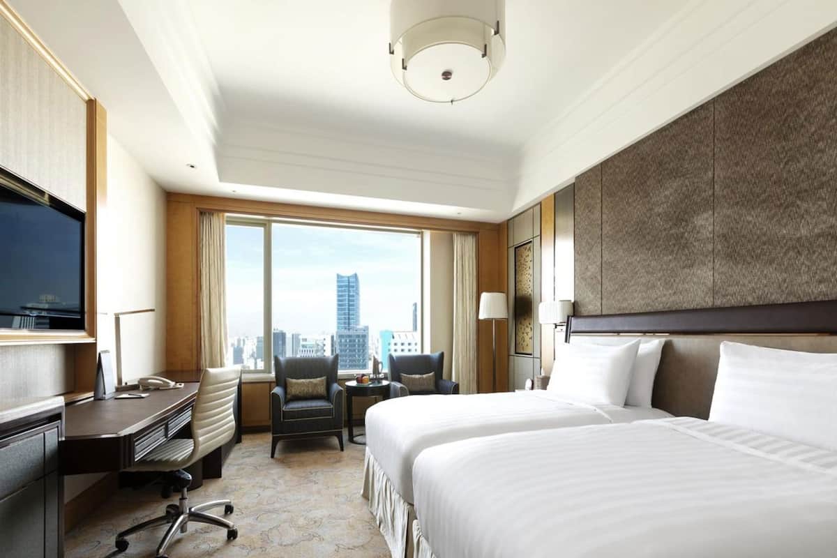Hotelkamer met een groot bed, een bureau met stoel, een televisie en uitzicht op de stad.