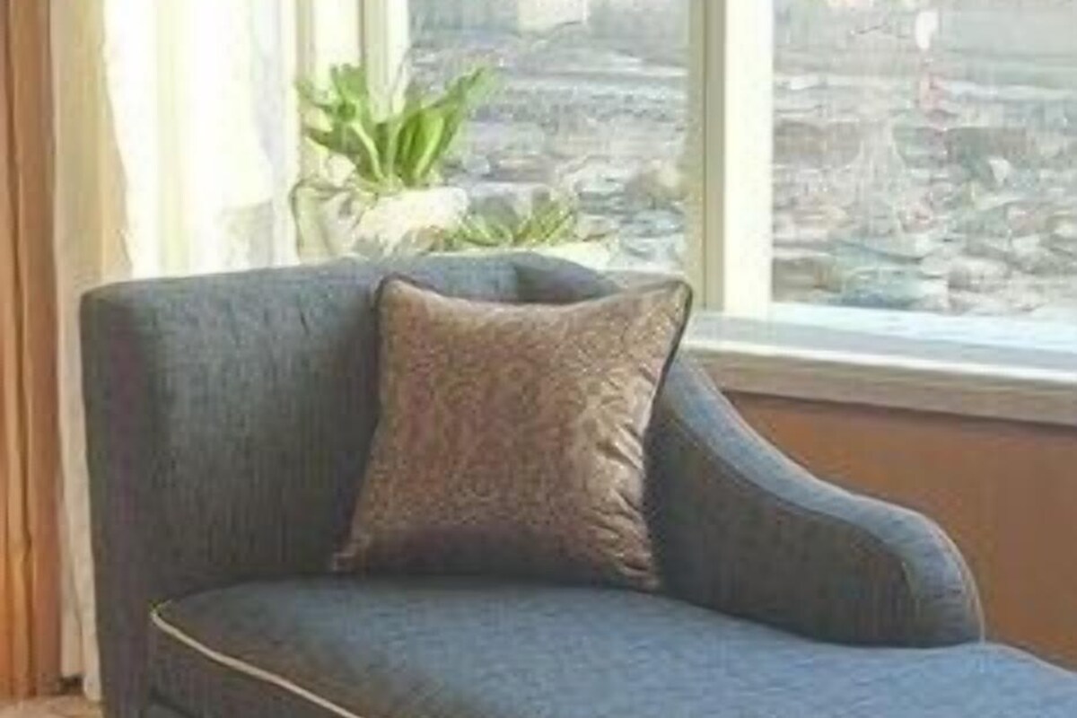 Un sofá de esquina con vista a un paisaje urbano a través de una ventana.