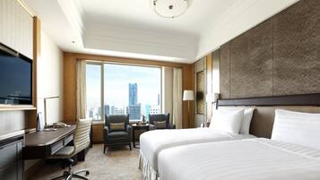 Habitación de hotel con una cama grande, un escritorio con silla, televisión y vistas a la ciudad.