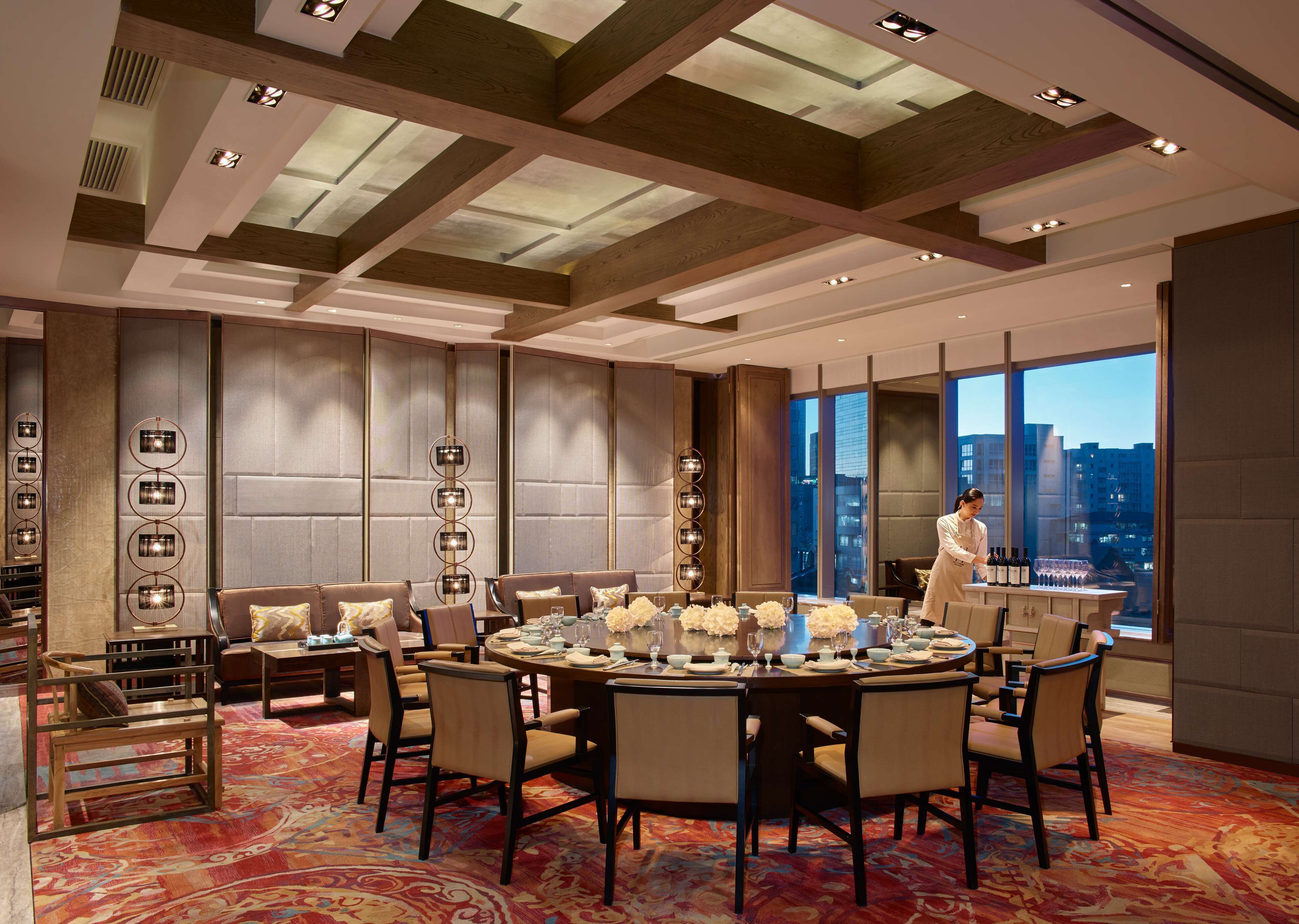 A modern hotel dining room with a round table set for six, surrounded by comfortable seating.