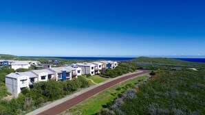 A coastal residential area with modern houses, a paved road, and a clear view of the ocean. - Margaret River Beach Apartments (Gnarabup)