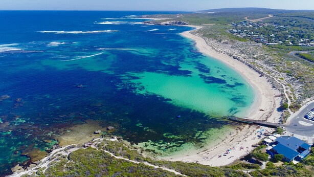 An aerial view of a coastal area with a beach, clear waters, and a bridge connecting the land to the water. - Margaret River Beach Apartments (Gnarabup)