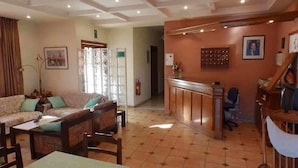 A spacious living area with a sofa set, a dining table, and a kitchen area with a counter and chairs. - Alexandra Hotel (Chania)
