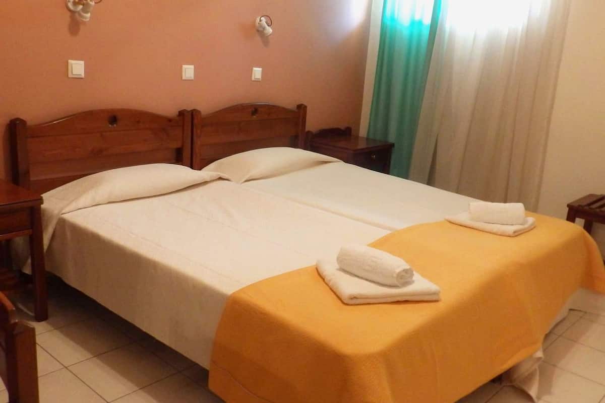 A double bed with a yellow bedspread and two white towels on it.