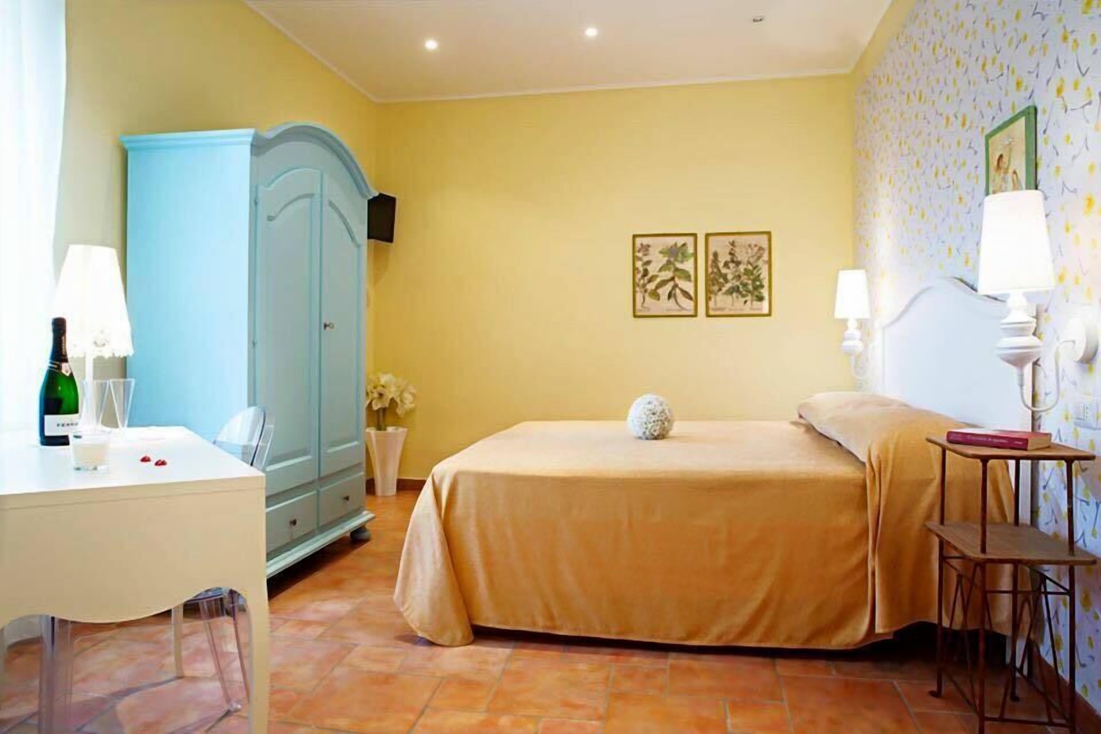 Een slaapkamer met een bed, een bureau, een kledingkast en een kleine tafel met een lamp.
