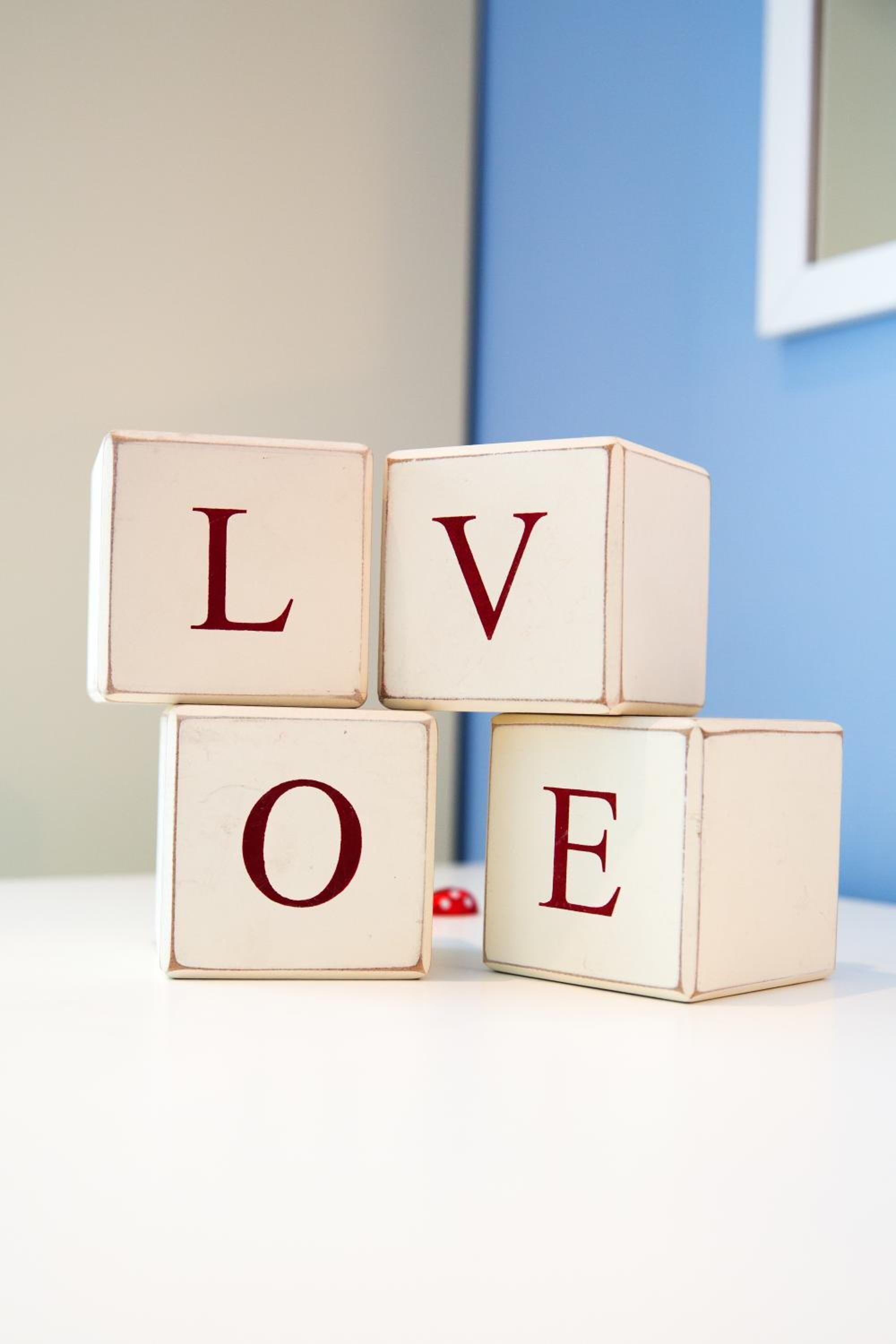 Wooden blocks with letters spelling "LOVE" stacked on a white surface.